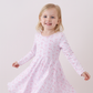 Young girl wearing a pink dress with a subtle pattern on a white background